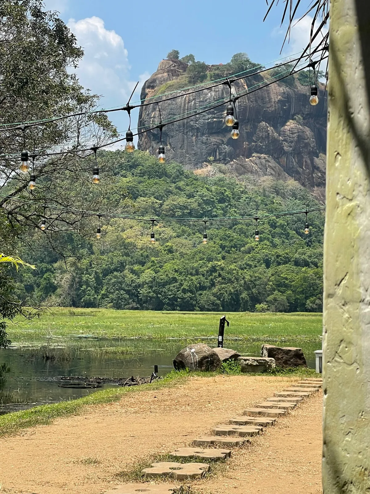 Sigiriya rock seen from the west with a stepping-stone path and trees